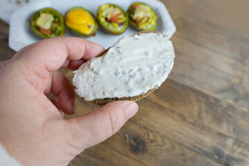 baked avocado stuffed with egg, vegetables, lie on a white dish, bread smeared with curd mass,...
