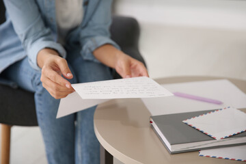 Young woman reading paper letter at home, closeup