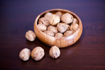 shelled walnuts in a wooden bowl. Blurry background.