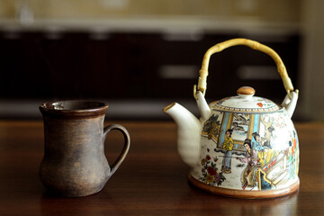 A table on which there is a mug of tea and a kettle.