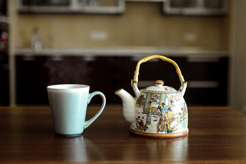 A table on which there is a mug of tea and a kettle.