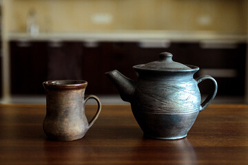A table on which there is a mug of tea and a kettle.