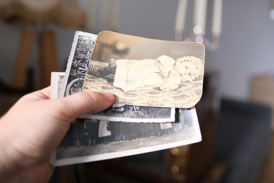 woman holding vintage photographs from 1960, concept of family tree, genealogy, childhood memories, connection with ancestors