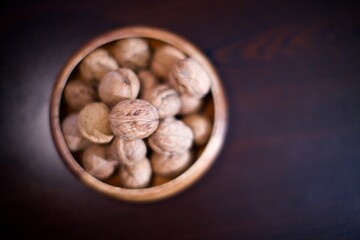 shelled walnuts in a wooden bowl. Blurry background.
