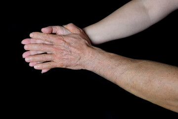 Fototapeta premium male and female hands together on black background, old skin with wrinkles and veins, concept of health, age-related changes, love, tender relationship of a couple in love, isolated image