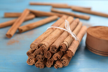 Aromatic cinnamon sticks on light blue wooden table, closeup
