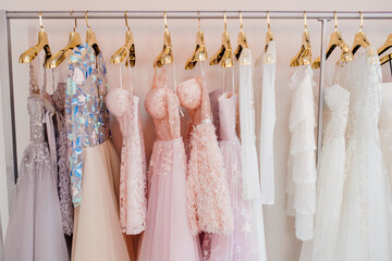 Collection of  beautiful evening dresses hanging on rack in dressing room. Clothing on hanger at...