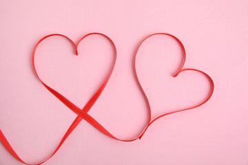 Hearts made of red ribbon on pink background, top view. Valentine's day celebration