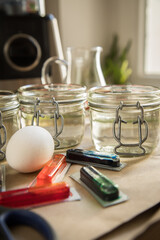 Bunte Ostereier Kaltfarben in Rot, Orange, Gelb, Blau, Grün in Verpackung auf Papier Unterlage mit Eier, Essig, Wasser, Gläser und Schere zum Färben zu Ostern