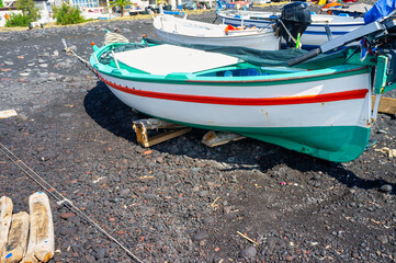 Some small wooden fishing boat, over the black volcanic sand beach of Lipari (Aeolian Archipelago, Southern Italy Mediterranean Sea), during summer season.