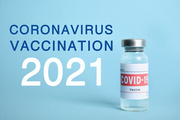 Vial with coronavirus vaccine on light blue background
