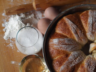 Ready made homemade buns, in a baking dish on a wooden background with the ingredients for their preparation. View from above.
