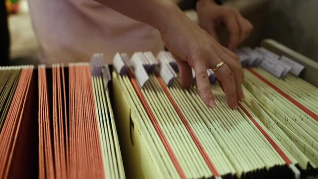 young woman goes through documents in home archive, looking for the right folder, concept family genealogy, memories, generational ties, museum historical materials
