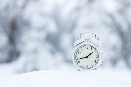 White Alarm Clock In The Winter Snow Forest. The Call Is Set For 3 Oclock In March Spring Is Coming Soon.