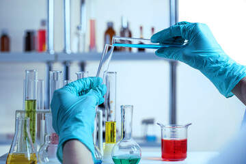 Gloved hands pouring liquid into test tubes