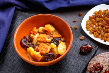 Jewish cuisine dish sweet tsimes with carrot dates vegetarian in a plate on a concrete background with a blue napkin.