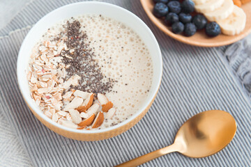 Healthy breakfast fruit smoothie bowl topped with almond, granola and chia seeds, snack banana and blueberry
