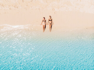 Couple of woman relaxing at paradise beach with sea. Aerial view
