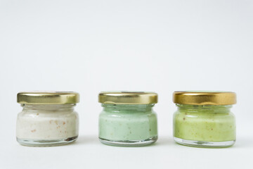 Three various jars with jam or honey in a row on white background. Home canning food.
