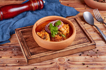 Stewed chicken, tomatoes, hot spices, Georgian cuisine, wooden background