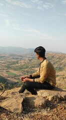 An Indian boy sitting on the top of a mountain