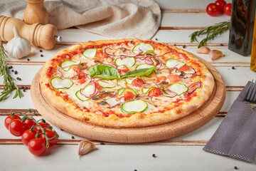 Pizza with slices, sauce and herbs, wooden white background