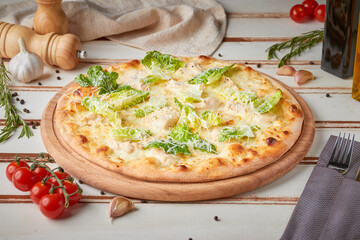 Pizza with slices, sauce and herbs, wooden white background