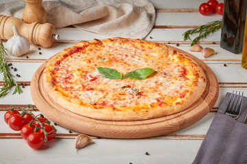 Pizza with slices, sauce and herbs, wooden white background