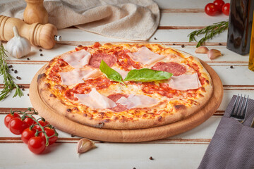 Pizza with slices, sauce and herbs, wooden white background