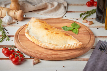 Pizza with slices, sauce and herbs, wooden white background