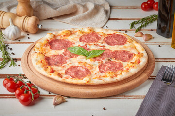 Pizza with slices, sauce and herbs, wooden white background