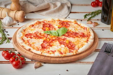 Pizza with slices, sauce and herbs, wooden white background