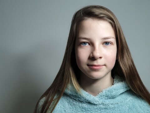 portrait of a teenage girl with blue eyes and a blue hoodie looking straight at the camera, the younger generation