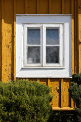 Old white wooden window and yellow facade of an old house.