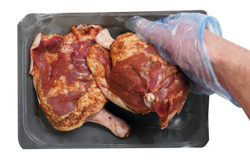 Two fresh uncooked duck legs on a grey plastic tray. Poultry product. Isolated on white background. Butcher holding one leg in his hand in blue plastic glove