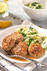 Chicken meatballs with raw zucchini in a plate on a gray concrete table. Delicious and dietary food.