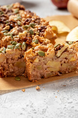 Gluten-free apple cake with walnuts, pumpkin seeds, cinnamon, and nutmeg. Freshly baked apple cake on baking paper close-up. Sweet vegetarian food, vegan dessert.