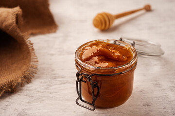 Thick buckwheat honey in an open glass jar on a wooden near the burlap