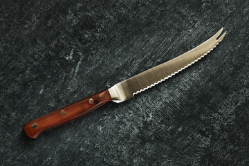 Specialized chefs kitchen tomato knife on gray grunge background, close up, top view