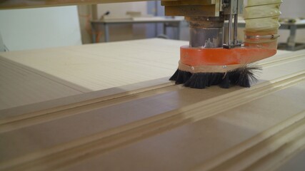 The CNC machine is working. Close-up of a numerical control machine cuts a tree. CNC tool. The machine cuts a drawing on a wooden facade.