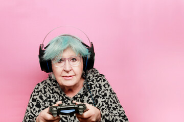 
modern grandmother with blue hair playing a video game with headphones and remote control has a camera