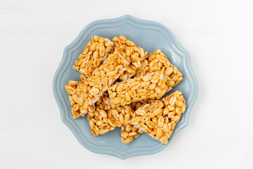 Peanut indian chikki (kozinaki) on plate on white background, top view