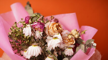 Close up of bouquet of wilted flowers. Variety of withered flowers in wrapping paper.