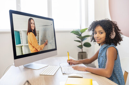Cheerful smart African schoolgirl recommends studying online, watching video classes with online teacher, practices individually with a tutor, studying on the distance. E-learn concept