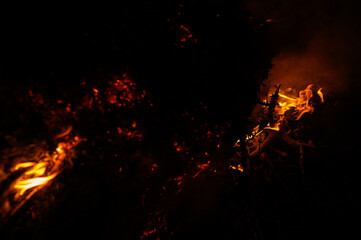 Fire and tongues of flame at night, bright light from the fire in the evening, light smoke from the fire.