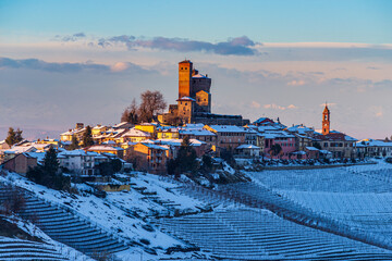 Italy Piedmont: wine yards unique landscape winter sunset, Serralunga d'Alba medieval village castle on hill top, the Alps snow capped mountains background, italian heritage grape agriculture