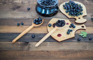Black currant jam with black currants fresh berries on a wooden background

