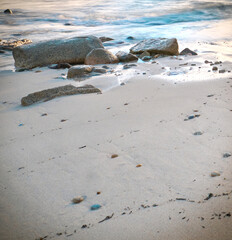 Sand background with stones on beach in sunset
