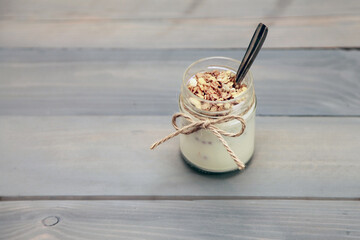 Homemade yogurt in a glass jar on a wooden table. Rustic style, selective focus.
