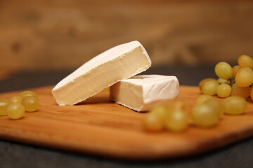 White brie or camembert cheese. Delicious appetizer cheese plate with white cheese and white grapes.